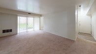 Located at 3400 Eastern Blvd in York, Pennsylvania, this single-floor unit offers a well-organized layout across a comfortable footprint. The living room is a standout feature, with plush wall-to-wall carpeting, clean white walls, and a full-width sliding glass door fitted with vertical blinds that invite an abundance of natural light and provide access to an outdoor area with green views. An adjacent carpeted space serves well as a dining area or secondary lounge. The galley-style kitchen is efficiently designed with warm honey-toned wood cabinetry lining both sides, dark laminate countertops, a double sink, and white appliances including a gas range, refrigerator, and dishwasher. Wood-look plank flooring runs throughout the kitchen, adding a durable and clean aesthetic. Multiple bedrooms feature soft carpeting and individual windows overlooking lush outdoor greenery, ensuring each room is bright and airy. Two bathrooms are finished with wood-look flooring and white fixtures; the full bath includes a tub-shower combination and a white vanity, while the half bath provides a clean, functional space. Overall, the unit presents a neutral, move-in-ready palette throughout.