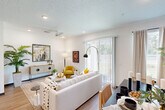 Located at 100 Inspire Way in St. Augustine, Florida, this two-story home offers a thoughtfully designed layout across two floors. The ground level includes a two-car garage with automatic openers, a modern kitchen and dining area, and convenient access to the upper level via a central staircase. The kitchen is outfitted with white shaker cabinetry, quartz countertops, a subway tile backsplash, stainless steel appliances, and wood-look flooring, creating a clean and functional space. The adjoining dining area features warm hardwood flooring and provides a welcoming atmosphere for entertaining. Three full bathrooms serve the home, including one with a glass-enclosed walk-in shower, wood-look tile flooring, and granite vanity countertops. The upper floor houses both bedrooms, an office, a hallway, and a dedicated closet. The primary bedroom features a tray ceiling, large windows with outdoor views, and plush carpeting. The second bedroom offers a bold accent wall and a built-in closet. The office provides a quiet, carpeted workspace with a built-in closet. A walk-in storage closet with built-in shelving adds practical storage. The exterior presents a clean white facade surrounded by lush Florida landscaping including palm trees and manicured lawn.