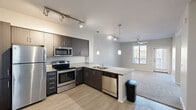 Located at 111 Dupont Circle in Phoenix, AZ, this 2-bedroom, 1-bathroom residence offers a thoughtfully designed single-floor layout. The open-concept kitchen and living area forms the heart of the home, where dark espresso cabinetry, granite countertops, and a full suite of stainless steel appliances — including a refrigerator, range, microwave, and dishwasher — create a sleek, modern aesthetic. A peninsula with pendant lighting provides additional counter space and serves as a natural divide between the kitchen and the adjoining living area. Track lighting and light wood-style flooring complete the kitchen's contemporary look. The living area features plush carpeting, a ceiling fan, and a window that brings in natural light and outdoor views of the surrounding landscape. Two carpeted bedrooms offer comfortable retreats with neutral tones and ample wall space. The primary bedroom is generously proportioned and includes a ceiling fan and a window with exterior views. The shared full bathroom is finished with a dark-cabinet vanity, granite countertop, a large mirror, modern light fixtures, and a combination tub and shower. A connecting hallway ties the layout together efficiently, contributing to the home's functional and cohesive flow.
