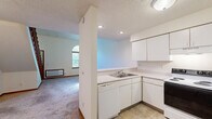 Located at 2234 Luann Ln in Madison, WI, this two-story home offers a thoughtfully arranged 1-bedroom, 1-bathroom layout across two floors. The main level provides a generous living and kitchen area, where an open-concept peninsula kitchen features white cabinetry, a dishwasher, electric range, refrigerator, and a double sink — all finished with light countertops and tile flooring. Recessed lighting and track lighting illuminate the space, while an arched window in the adjacent living area fills the room with natural light. Soft carpet throughout the living area adds warmth and comfort. The upper floor houses the spacious primary bedroom, highlighted by soaring vaulted ceilings and a skylight that floods the room with natural light. A dedicated walk-in closet with built-in shelving provides ample storage. The full bathroom is clean and functional, complete with a tub-shower combination, vanity with storage, and light flooring. Warm wood-toned trim and doors are consistent throughout both floors, lending a cohesive, classic feel to the home. Mature trees surrounding the exterior provide a serene, leafy setting visible from the arched living room window.
