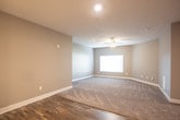 This single-story unit offers a well-designed open-concept layout that seamlessly connects the living and kitchen areas. The living space features neutral gray walls, plush wall-to-wall carpeting, and ceiling fans with integrated lighting, creating a comfortable and functional environment. Recessed lighting and pendant fixtures provide ample illumination throughout.

The kitchen is a standout feature, showcasing dark espresso cabinetry, granite countertops, and a full suite of stainless steel appliances, including a refrigerator, range, and microwave. A peninsula with a built-in sink and pendant lighting above bridges the kitchen and living area, making it ideal for both everyday use and entertaining. Wood-look plank flooring runs throughout the kitchen and entry areas, adding warmth and durability.

The bedrooms are carpeted and generously proportioned, each equipped with ceiling fans and natural light from windows fitted with blinds. One bedroom includes access to a spacious walk-in closet outfitted with built-in shelving, hanging rods, and a dedicated folding surface. The bathroom features a full-size soaking tub and shower combination with clean white surrounds. The unit's cohesive gray color palette and modern finishes contribute to a clean, contemporary ambiance throughout.