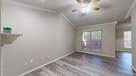 This single-story residence offers a thoughtfully designed layout that balances comfort and functionality. Throughout the home, light gray hardwood-style flooring provides a clean, cohesive aesthetic, while crown molding and textured ceilings add a classic architectural touch. Ceiling fans are present in every room, contributing to year-round comfort.

The living area is a standout space, featuring vaulted ceilings that create an open, airy feel, along with a white-mantled fireplace that serves as an attractive focal point. Natural light filters in through blinds-fitted windows, enhancing the warm, neutral color palette of the walls.

The kitchen is well-equipped with warm honey-toned cabinetry, a tile backsplash, light quartz-style countertops, and stainless steel appliances including a gas range and microwave. A breakfast bar connects the kitchen to the adjacent living space, making it ideal for casual dining and entertaining.

The bedrooms are generously proportioned, with vaulted or standard ceilings, ample natural light, and dedicated closet space. One bedroom features mirrored sliding closet doors for added functionality.

The bathroom includes a wooden-framed vanity mirror, a single-basin sink with quartz-style countertops, and in-unit laundry access, adding significant convenience to daily living.
