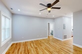 Located in Chicago's Rogers Park neighborhood, this 3-bedroom, 1-bathroom unit at 1145 W Lunt offers a clean, modern aesthetic throughout its single-floor layout. Warm honey-toned hardwood floors flow seamlessly through every room, complemented by soft gray walls and crisp white trim that create a bright, cohesive feel.

The generously sized primary bedroom is a standout, offering ample space for a full furniture arrangement and featuring a ceiling fan with recessed lighting. Additional bedrooms include one with dual windows that invite natural light, and another with a louvered bi-fold closet. Two closets provide practical storage throughout the unit.

The renovated kitchen is well-appointed with white shaker-style cabinetry, white quartz countertops, a classic subway tile backsplash, and a full suite of stainless steel appliances including a dishwasher, range, microwave, and refrigerator. A window above the sink adds natural light to the space.

The bathroom features floor-to-ceiling white subway tile in the tub/shower surround, chrome fixtures, and a natural light source via a window. A long hallway connects the kitchen to the living areas, reinforcing the unit's efficient and open layout. Recessed lighting and ceiling fans throughout ensure comfort and functionality in every room.