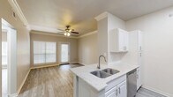 Located at 2200 Riverfront Dr in Little Rock, Arkansas, this one-bedroom, one-bathroom residence offers a thoughtfully designed single-floor layout with contemporary finishes throughout. Light gray wood-look flooring flows consistently across every room, complementing the neutral warm and cool-toned walls that create a clean, cohesive aesthetic.

The open-concept kitchen and living area forms the heart of the home. The kitchen is outfitted with crisp white cabinetry, granite-speckled countertops, a double-basin stainless steel sink set into a peninsula, and a full suite of stainless steel appliances including a refrigerator, range, microwave, and dishwasher. The adjacent living area benefits from crown molding, a ceiling fan, and a glass-paned door that invites natural light and outdoor access.

The bedroom is a comfortable retreat featuring a ceiling fan, natural light from a large window, crown molding, and direct access to a spacious walk-in closet equipped with multi-level wire shelving for ample storage.

The bathroom offers a clean, functional design with a granite-topped vanity, a large mirror, and a tub-shower combination. Consistent wood-look flooring ties the space together seamlessly. A hallway connects the main living areas, completing this well-appointed and efficiently organized home.