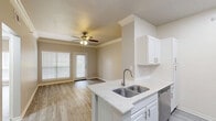 Located at 2200 Riverfront Dr in Little Rock, Arkansas, this one-bedroom, one-bathroom residence offers a thoughtfully designed single-floor layout with contemporary finishes throughout. Light gray wood-look flooring flows consistently across every room, complementing the neutral warm and cool-toned walls that create a clean, cohesive aesthetic.

The open-concept kitchen and living area forms the heart of the home. The kitchen is outfitted with crisp white cabinetry, granite-speckled countertops, a double-basin stainless steel sink set into a peninsula, and a full suite of stainless steel appliances including a refrigerator, range, microwave, and dishwasher. The adjacent living area benefits from crown molding, a ceiling fan, and a glass-paned door that invites natural light and outdoor access.

The bedroom is a comfortable retreat featuring a ceiling fan, natural light from a large window, crown molding, and direct access to a spacious walk-in closet equipped with multi-level wire shelving for ample storage.

The bathroom offers a clean, functional design with a granite-topped vanity, a large mirror, and a tub-shower combination. Consistent wood-look flooring ties the space together seamlessly. A hallway connects the main living areas, completing this well-appointed and efficiently organized home.