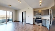 Located at 1711 19th Ave S in Nashville, TN, this one-bedroom, one-bathroom unit offers a thoughtfully designed layout that maximizes its compact footprint. The open-concept living and kitchen area features wood-style plank flooring, track lighting, and neutral walls that create a bright, contemporary atmosphere. The kitchen is well-appointed with gray shaker-style cabinetry, dark countertops, a white subway tile backsplash, and a full suite of stainless steel appliances, including a range, microwave, dishwasher, and refrigerator. The living area opens through sliding glass doors to a private balcony, bringing in generous natural light.

The bedroom is carpeted and features a ceiling fan, a window with outdoor views, and a distinctive sliding barn-style door with a frosted glass panel. A dedicated closet provides additional storage. The bathroom includes a tiled tub-and-shower combination with a built-in niche, wood-style flooring, and a vanity with blue cabinetry and dark countertops. In-unit laundry hookups are also present, adding everyday convenience to this modern Nashville residence.