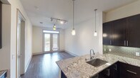 Located at 3535 Bluffs Ln in Grapevine, TX, this well-appointed single-floor residence offers a thoughtfully designed open-concept layout with modern finishes throughout. The kitchen is a standout feature, showcasing rich dark cabinetry that extends to the ceiling, sleek granite countertops, a subway tile backsplash, and a full suite of stainless steel appliances including a range, microwave, and refrigerator. A peninsula with an undermount sink and pendant lighting connects the kitchen seamlessly to the main living area, making it ideal for both everyday living and entertaining. The living space is bathed in natural light, highlighted by hardwood flooring, a ceiling fan, track lighting, and French doors that open to an outdoor balcony. A dedicated wet bar area with dark cabinetry provides additional functionality adjacent to the main living space. The bedroom features plush carpeting, a ceiling fan, and a bright window with exterior views. The bathroom is finished with large-format tile flooring, dark vanity cabinetry, and provides direct access to a walk-in closet with built-in shelving and hanging rods. Throughout the residence, a neutral color palette and quality materials create a clean, contemporary ambiance.