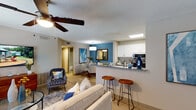 This single-floor residence at 840 Warrenton Rd in Fredericksburg, VA offers a thoughtfully designed open-concept layout with light wood-style flooring throughout. The living area is bright and welcoming, featuring a large window that draws in natural light, a ceiling fan, and ample space for comfortable furnishings.

The kitchen is positioned adjacent to the living space and features white upper cabinetry, two-tone lower cabinetry in gray, granite countertops, stainless steel appliances including a range and built-in microwave, and a breakfast bar with seating. A skylight above adds additional natural illumination.

The dedicated dining area is distinguished by a bold blue accent wall, chair rail molding, a framed wall mirror, and pendant lighting, creating an intimate yet stylish setting.

The bedroom is generously sized with neutral gray walls, a large window with decorative curtains, and wood-style flooring. Two bathrooms serve the unit, each featuring white vanity cabinetry, granite countertops, framed mirrors, and tub/shower combinations. A louvered closet door provides convenient storage access off the kitchen. The overall ambiance is modern and cohesive throughout.