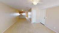 This single-floor residence offers a comfortable and functional layout designed for everyday living. The open-concept living area greets you at the entry, featuring neutral-toned carpet, a ceiling fan with light fixture, and a tiled entryway. The space flows naturally toward the kitchen, which is equipped with light oak cabinetry, speckled countertops, black appliances including an electric range, microwave, and dishwasher, and a skylight-style ceiling panel that brightens the room.

The two bedrooms are finished with plush carpet and ceiling fans, providing a cozy and restful atmosphere. One bedroom features mirrored sliding closet doors with a black frame, while the other also includes a mirrored wardrobe and windows that invite natural light. The full bathroom is clean and simply appointed, featuring a tub-shower combo with white surrounds, a speckled countertop vanity, and well-lit mirror.

A standout feature of this residence is the private balcony, accessible via dual sliding glass doors. The balcony offers an elevated outdoor view of the surrounding area, including swaying palm trees, a sparkling community pool, and lush landscaping below — a pleasant retreat that adds significant charm to this well-rounded home.