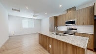 Located at 6250 S 40th St in Phoenix, AZ, this efficiently designed one-bedroom, one-bathroom unit offers a thoughtful open-concept floor plan with clean, modern finishes throughout. Light wood-style flooring runs continuously across the entire space, creating a cohesive and airy feel.

The kitchen serves as the centerpiece of the living area and is outfitted with warm wood-toned cabinetry that extends to the ceiling for maximum storage. A granite-topped island with an integrated sink provides both prep space and a natural division between the kitchen and living area. Stainless steel appliances — including a range, microwave, and refrigerator — complement the subway tile backsplash, lending a contemporary edge to the design. Recessed lighting illuminates the space effectively, while natural light enters through blinds-fitted windows.

The living area is open and bright, featuring a ceiling fan, recessed lighting, and a clean, neutral palette that offers flexibility for various furniture arrangements.

The bedroom is a comfortable, well-proportioned retreat with a ceiling fan, two windows that invite natural light, and a calm, neutral finish that promotes restfulness.

The bathroom includes a full tub-shower combination with built-in shelving, a white surround, and a window above for added ventilation and light. Light wood flooring continues here as well, maintaining consistency with the rest of the home.