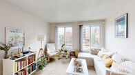 Located at 615 SE 15th Ave in Minneapolis, MN, this one-bedroom, one-bathroom unit offers a well-organized, single-floor layout designed for efficient, comfortable living. The open living area is the heart of the home, featuring soft carpeting and an abundance of natural light streaming through multiple large windows that frame views of the surrounding Minneapolis cityscape. The space is versatile enough to accommodate both a dining area and a dedicated workspace alongside a comfortable seating arrangement. A built-in baseboard heating unit runs along the perimeter, ensuring warmth throughout the colder Minnesota months. The bedroom is a cozy, carpeted retreat with a large window fitted with vertical blinds and a wall-mounted air conditioning unit for year-round climate control. The bathroom features classic white tile on both the floor and walls, a pedestal sink, a mirrored medicine cabinet, and a shower-tub combination. The galley-style kitchen includes warm wood cabinetry, a double-basin sink, a full-size refrigerator, and tile flooring, providing all the essentials in a compact and practical layout. A hallway connects the rooms, adding a sense of defined flow throughout the unit. Textured ceilings are consistent throughout the space, lending a classic character to this efficiently designed Minneapolis home.