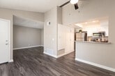 This single-floor residence offers a thoughtfully designed open-concept layout that seamlessly connects the living area to the kitchen. The living space is highlighted by soaring vaulted ceilings, rich wood-tone laminate flooring, and a ceiling fan with built-in lighting. Natural light pours in through multiple windows fitted with blinds, while a sliding glass door with vertical blinds opens to a balcony overlooking lush greenery.

The kitchen is efficiently designed with crisp white cabinetry, granite countertops, and a full suite of stainless steel appliances, including a refrigerator, electric range, and over-the-range microwave. A peninsula counter provides a natural division between the kitchen and living area, enhancing the open flow of the space.

The bathroom is finished with a white vanity featuring granite countertops, a large mirror with overhead lighting, and a shower-tub combination with a decorative curtain. Wood-tone flooring continues throughout, maintaining a cohesive aesthetic.

The entryway is bright and welcoming, with a large sliding door offering views of the outdoors and ample natural light. Throughout the space, neutral tones, textured ceilings, and clean white trim work together to create a comfortable and well-appointed interior.