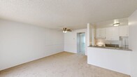 Located at 20939 Parthenia St in Canoga Park, CA, this single-story unit offers a thoughtfully arranged floor plan encompassing one bedroom, one bathroom, a kitchen, and a dedicated closet. The overall layout is compact yet functional, making efficient use of its available space.

The galley-style kitchen features granite-look countertops, white cabinetry with ample upper and lower storage, a stainless steel double sink, a refrigerator, and an electric range with hood ventilation. Wood-look flooring adds warmth and durability to the kitchen area.

The living area connects directly to the kitchen and is finished with neutral carpet and a ceiling fan, lending a comfortable, casual atmosphere. The bedroom is carpeted and receives natural light through a window fitted with vertical blinds. A textured ceiling is present throughout. A dedicated walk-in closet off the bedroom provides generous storage, featuring wrap-around hanging rods and carpeted flooring.

The bathroom includes a vanity with granite-look countertops, white cabinetry, a large mirror, a wall-mounted light fixture, and wood-look flooring, maintaining a clean and cohesive aesthetic consistent with the rest of the unit.