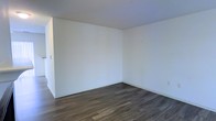 This two-story space offers a clean and minimalist aesthetic that provides a versatile, move-in-ready environment. The interior is defined by bright, white walls that create a sense of openness and allow light to reflect evenly across each room. Underfoot, rich dark hardwood-style flooring runs throughout, offering a striking contrast to the light walls and adding a sense of warmth and continuity to the overall design. The neutral color palette creates a blank canvas that is highly adaptable to a variety of uses and furnishing styles. The layout spans two floors, providing a natural separation of spaces that allows for flexible use of each level. Smooth white ceilings complement the walls, contributing to the airy, uncluttered atmosphere. Clean baseboards and well-defined corners reflect careful finishing throughout the interior. The straightforward, no-frills design keeps the focus on functionality and practicality, making this space suitable for a wide range of occupants. Overall, the space presents a modern, understated character that balances simplicity with everyday livability.