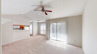 Located on Quail Boulevard in Austin, TX, this 2-bedroom, 2-bathroom residence offers a practical and comfortable single-floor layout. The living room is a standout space, featuring soaring vaulted ceilings with a ceiling fan, soft carpet flooring, and a tile-surround fireplace with a white mantel that serves as a focal point. A sliding glass door floods the room with natural light and provides outdoor access. The kitchen is open to the living area via a pass-through breakfast bar and is equipped with warm wood cabinetry, white appliances including a refrigerator, electric range, and microwave, plus durable hardwood-style flooring. The primary bedroom is generously sized with plush carpet, ample wall space, and connects to a private bathroom featuring a wood-toned vanity, a soaking tub, and hardwood-style floors. The second bedroom includes a built-in closet with sliding doors and its own carpeted comfort. The second bathroom offers a tub-shower combo and hardwood-style flooring. A hallway and dedicated closet round out the layout, providing practical storage solutions throughout this well-organized Austin home.