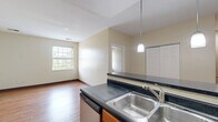 Located in Pittsburgh's South Side neighborhood, this two-story home offers a well-organized layout spread across two floors. The main level features an open-concept kitchen and living area connected by rich hardwood flooring. The kitchen is equipped with stainless steel appliances, including a range, microwave, and dishwasher, complemented by warm wood cabinetry and dark countertops. A peninsula with bar-top seating and pendant lighting adds both function and style, creating a natural gathering point that flows into the spacious living room. Natural light enters through several windows, brightening the neutral-toned walls throughout.

The upper level hosts both bedrooms, each carpeted for comfort. The primary bedroom is a generously sized retreat featuring a skylight that fills the room with natural light, along with angled ceilings that lend architectural character. The second bedroom is well-proportioned with a window and ample closet space. Notably, the home includes five closets total, providing exceptional storage throughout. The full bathroom features tile flooring, a tub/shower combo, a vanity with stone-look countertop, and wood cabinetry. Two staircases connect the floors, offering convenient circulation through the home.
