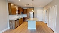 This contemporary 1-bedroom apartment in Billerica, MA, offers 790 square feet of thoughtfully designed living space. The open-concept layout seamlessly integrates the kitchen, living, and dining areas, creating a spacious feel. The kitchen is a standout feature, boasting warm wood cabinetry, stainless steel appliances, and a generous granite-topped island. Large windows throughout flood the space with natural light, while modern fixtures and finishes add a touch of sophistication. The bedroom, measuring 200 square feet, provides ample space and features a ceiling fan for comfort. The bathroom showcases a wood vanity with a granite countertop and a large mirror. Light-toned wood-look flooring unifies the space, complementing the neutral wall colors. Practical amenities include recessed lighting, window blinds, and in-unit climate control. This apartment combines style and functionality, offering a comfortable and contemporary living environment.