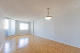 Located at 30 Elm Dr E in Mississauga, Ontario, this one-bedroom, one-bathroom unit offers a practical and well-organized layout across a single floor. The combined kitchen and living area forms the heart of the unit, where warm parquet flooring extends throughout, adding a classic character to the space. The living room is bright and open, benefiting from large windows fitted with vertical blinds and sliding balcony access that draws in natural light and provides urban views of the surrounding cityscape.

The kitchen is efficiently designed with white cabinetry — both upper and lower — complemented by granite-style countertops, a stainless sink, and full-size refrigerator. Light vinyl flooring ties the kitchen area together cleanly.

The bedroom is a comfortable size, featuring the same warm parquet flooring, a window with natural light, and direct access to a dedicated walk-in closet complete with built-in hanging rods — a practical storage solution.

The bathroom is finished with full white tile surround, a tub-shower combination, and a mirrored medicine cabinet. A hallway connects the main rooms, with a textured ceiling consistent throughout the unit. The space is clean, neutral, and move-in ready.