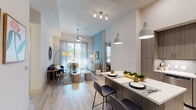 This well-appointed single-floor residence offers a thoughtfully designed open-concept layout that seamlessly connects the kitchen, dining, and living areas. The kitchen is a standout feature, showcasing wood-grain cabinetry, a subway tile backsplash, white quartz countertops, and a full suite of stainless steel appliances. A central island with bar seating and pendant lighting serves as both a functional workspace and casual dining spot. The living area is bright and welcoming, with light hardwood-style flooring, a ceiling fan, and large sliding glass doors that invite ample natural light and provide outdoor views. A teal accent wall adds a pop of color and visual interest to the space. The bedroom is a calm retreat, featuring soft neutral tones, a ceiling fan, and sheer window treatments that allow natural light to filter through. Two walk-in closets offer generous storage with adjustable shelving systems and built-in drawers. The bathroom is finished with marble-look tile flooring, wood-grain vanity cabinetry, a white quartz countertop, a large mirror, and a tub-shower combination. Throughout the residence, consistent light-toned flooring and a neutral color palette create a cohesive, modern aesthetic.