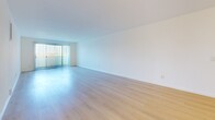 Located at 3111 Fourth St in Santa Monica, CA, this 1-bedroom, 2-bathroom residence offers a clean, modern aesthetic throughout its well-organized single-floor layout. Light wood flooring runs continuously across all rooms, creating a cohesive and airy feel.

The open living area is generously proportioned, bathed in natural light from sliding glass doors fitted with vertical blinds that lead to an outdoor space and frame views of the surrounding neighborhood. The adjacent galley-style kitchen is well-appointed with white flat-panel cabinetry, white quartz countertops, stainless steel appliances including a gas range, refrigerator, dishwasher, and microwave, plus a matte black faucet over a single-basin sink.

The bedroom is a comfortable size, also featuring sliding glass doors with vertical blinds and a ceiling fan with integrated lighting. A dedicated walk-in closet with built-in shelving and hanging rods provides ample storage.

Both bathrooms are finished in a crisp, minimalist style. One features a soaking tub with a subway-tiled surround and a recessed niche, while the other includes a sleek floating vanity with a white countertop, undermount sink, matte black fixtures, and a large wall mirror. The overall ambiance is bright, clean, and contemporary.