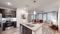 Located at 20102 Cypress Rose Hill Road in Tomball, Texas, this thoughtfully designed 2-bedroom, 2-bathroom residence offers a comfortable and modern single-floor layout. The open-concept living and kitchen area serves as the heart of the home, where wood-look flooring, recessed lighting, and large windows invite abundant natural light. The kitchen is equipped with dark espresso cabinetry, stainless steel appliances, a subway tile backsplash, and a granite-topped center island with pendant lighting and a deep single-basin sink — ideal for both cooking and entertaining. The living room features a ceiling fan, floor-to-ceiling windows, and direct access to an outdoor area. The primary bedroom is a serene retreat with a large window, ceiling fan, and a well-organized walk-in closet featuring multi-level shelving and hanging rods. The en-suite bathroom includes a granite vanity with dark cabinetry, a glass-enclosed walk-in shower with white tile surround, and wood-look flooring. The second bedroom mirrors the light and airy aesthetic with ample natural light and closet space. A dedicated in-unit laundry area with side-by-side washer and dryer and overhead shelving adds everyday convenience to this well-rounded residence.