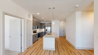 Located at 4245 Bobtown Rd in Garland, TX, this well-appointed 2-bedroom, 2-bathroom residence offers a thoughtfully designed single-floor layout. The heart of the home is a bright, open-concept space combining the kitchen, dining, and living areas. The modern kitchen is a standout, featuring sleek gray shaker cabinets, white subway tile backsplash, stainless steel appliances including a French door refrigerator and electric range, and a large center island with a quartz countertop, undermount sink, and stylish pendant lighting overhead. Light wood-tone flooring flows throughout the main living areas, enhancing the clean, contemporary aesthetic. The spacious primary bedroom benefits from multiple windows that invite natural light, complemented by a ceiling fan and its own en-suite bathroom. The primary bath includes a dual-sink vanity with gray cabinetry, quartz countertops, and a glass-enclosed walk-in shower with subway tile surround. The second bedroom features plush carpet and a window with outdoor views. The second bathroom offers a tub-shower combo with matching tile finishes. Additional highlights include three closets, a dedicated pantry, in-unit laundry, and a private balcony. Recessed lighting throughout adds a polished finishing touch.
