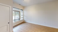 This contemporary 610 square foot apartment offers a thoughtfully designed living space. The single-floor layout comprises one bedroom, one bathroom, and an open-concept kitchen and living area. The primary bedroom, measuring 160 square feet, provides a comfortable retreat.

The interior showcases a modern aesthetic with clean lines and a neutral color palette. Light-toned wooden flooring runs throughout the main living areas, complemented by plush carpeting in the bedroom for added comfort. Large windows with horizontal blinds allow abundant natural light to flood the space, creating an airy atmosphere.

The kitchen is a highlight, featuring sleek white cabinetry, stainless steel appliances, and a stylish pendant light over the island. The countertops appear to be quartz or a similar high-quality material, offering both durability and elegance. A U-shaped layout maximizes functionality in the compact space.

The bathroom continues the contemporary theme with a floating vanity, modern fixtures, and a glass-enclosed shower. Strategic lighting and minimalist design elements contribute to the overall sense of spaciousness.

Throughout the apartment, recessed lighting and carefully placed fixtures provide layered illumination options. The open floor plan and thoughtful design make this compact space feel larger and more versatile, ideal for modern urban living.