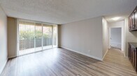 Located at 7707 Mission Gorge in San Diego, Unit #49 is a single-floor residence designed with a clean, neutral aesthetic throughout. The spacious living area is a standout feature, showcasing light wood-style flooring, a textured ceiling, and a full wall of sliding glass doors dressed with vertical blinds that open to a private balcony with lush outdoor views. Natural light fills the room, creating a bright and welcoming atmosphere. A wall-mounted climate control unit provides convenient temperature management. The kitchen is thoughtfully laid out in a galley style, featuring rich dark cabinetry with brushed nickel hardware, dark countertops, a stainless steel refrigerator, and matching appliances — offering a bold contrast to the otherwise light interior. The bedroom is generously sized, finished with plush wall-to-wall carpeting and a textured ceiling. It is equipped with an expansive mirrored sliding closet system that spans nearly the full width of the room, providing substantial storage. The bathroom includes a clean, white tub and shower combo with chrome fixtures. Neutral tones, practical finishes, and functional layouts define this well-maintained San Diego residence.