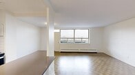 Located on the 6th floor at 1450 Sheppard Ave W in Toronto, this 2-bedroom, 1-bathroom unit offers a well-organized layout across a single floor. The open-concept kitchen and living area forms the heart of the unit, where a modern kitchen features white cabinetry, subway tile backsplash, dark countertops, stainless steel appliances including a refrigerator, dishwasher, and range, and light tile flooring. A breakfast bar peninsula connects the kitchen to the living area, which is finished with classic parquet wood flooring found throughout the unit. Large windows in the living room flood the space with natural light and provide open city views. Both bedrooms are generously proportioned, each featuring parquet flooring, neutral white walls, and large windows with baseboard heating units beneath them, offering views of the surrounding Toronto neighbourhood. The primary bedroom is a comfortable size, providing ample space for furnishings. The bathroom is finished with clean white subway tile surrounding a soaker tub and shower combination with chrome fixtures and a frosted window for natural light. A hallway connects all rooms, completing the functional and straightforward layout of this well-lit urban residence.