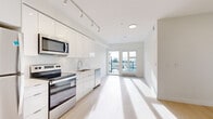 This well-appointed 2-bedroom, 2-bathroom unit offers a thoughtfully designed open-concept layout filled with natural light. The kitchen is a standout feature, showcasing high-gloss white cabinetry extending to the ceiling, a white subway tile backsplash, light quartz countertops, and a full suite of stainless steel appliances including a refrigerator, electric range, built-in microwave, and dishwasher. Track lighting overhead adds a modern touch and enhances the bright, airy atmosphere. The kitchen flows seamlessly into the living area, which is finished with light-toned flooring throughout and leads to a private balcony accessible via glass-paneled French doors, offering open views of the surrounding area. The spacious primary bedroom features the same light hardwood-style flooring, generous closet space with a sliding door, and abundant natural light. Both bathrooms are finished in a clean, contemporary style — one featuring a soaker tub with chrome fixtures and light wood-toned flooring, and the other with a sleek white vanity and modern cabinetry. Throughout the unit, crisp white walls, clean lines, and consistent finishes create a cohesive and inviting modern aesthetic.