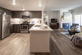 Located in Chino Hills, California, this well-appointed single-floor residence offers a thoughtfully designed open-concept layout that seamlessly connects the kitchen, dining, and living areas. The kitchen is a standout feature, showcasing dark espresso cabinetry, crisp white quartz countertops, a textured tile backsplash, stainless steel appliances including a gas range and built-in microwave, and a central island with a sink — ideal for both cooking and casual entertaining. Adjacent to the kitchen, the dining area provides an intimate space with wood-look flooring that carries throughout the main living areas. The living room is bright and welcoming, with a cozy fireplace, a sliding glass door opening to a private patio, and windows that invite natural light. Both bedrooms are carpeted for comfort and feature ceiling fans, ample natural light through slatted windows, and generous space. The primary bathroom offers a dual-sink vanity with dark wood cabinetry and a soaking tub, while the second bathroom features a single vanity and a glass-enclosed shower. Wood-look flooring flows consistently through the main areas, tying the home's modern aesthetic together cohesively.