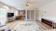 Located at 24 E 17th St in Tulsa, Oklahoma, this one-bedroom, one-bathroom unit offers a thoughtfully arranged single-floor layout with a warm blend of historic character and functional design. Hardwood floors run throughout, tying the living, sleeping, and kitchen spaces together cohesively.

The living area is open and inviting, anchored by a ceiling fan with light fixture and framed by a striking exposed brick accent wall that adds texture and industrial charm. French doors with glass pane detailing separate the bedroom from the main living space, allowing light to flow through while maintaining privacy. Windows on multiple walls bring in natural light and provide views to the outside.

The bedroom is generously proportioned relative to the overall footprint, offering ample space for furnishings and personal comfort. Clean white walls and recessed lighting keep the room feeling bright and airy.

The kitchen features warm honey-toned cabinetry, dark granite countertops, a stainless steel side-by-side refrigerator, and a full suite of appliances. The exposed brick wall continues here, reinforcing the unit's distinctive character while complementing the light hardwood floors.

The bathroom retains a vintage aesthetic with bold red mosaic tile flooring, white subway tile walls, a soaking tub with shower, a wood vanity, and a window that provides natural ventilation and light.