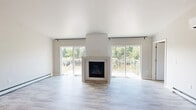 This well-appointed single-floor home in Marinette, Wisconsin offers a thoughtfully designed layout with two bedrooms, two bathrooms, and two closets. The open-concept living room is a standout, boasting soaring vaulted ceilings, light-toned luxury vinyl plank flooring, and a sleek corner fireplace flanked by two large sliding glass doors that flood the space with natural light and provide direct access to a spacious outdoor deck with views of surrounding greenery.

The kitchen is well-equipped with granite countertops, taupe shaker-style cabinetry, stainless steel appliances, a center island with pendant lighting, and vaulted ceilings that carry the airy feel from the living area.

The primary bedroom is generously sized, featuring a ceiling fan, a baseboard heating unit, and a window with outdoor views. The second bedroom similarly offers a ceiling fan, multiple windows, and the same warm flooring found throughout the home.

Both bathrooms are finished with wood-look flooring and clean, neutral tones. One bathroom features a granite-topped vanity, while the other includes a walk-in shower. Storage is well addressed with two dedicated closets, including a spacious walk-in closet with wire shelving. Baseboard heating is present throughout.