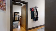 Located at 675 N Main in the heart of downtown Winston-Salem, NC, this one-bedroom, one-bathroom loft delivers a compelling blend of industrial character and modern comfort. The open-concept living and kitchen area anchors the space, featuring warm hardwood floors and soaring ceilings that amplify the sense of openness. Large, multi-pane factory-style windows flood the living room with natural light while offering views of the surrounding urban landscape — a signature nod to the building's industrial heritage.

The kitchen is well-appointed with dark wood cabinetry, granite countertops, stainless steel appliances, and pendant lighting, flowing seamlessly into the living area via a breakfast bar. Exposed ductwork overhead reinforces the loft's industrial aesthetic throughout.

The bedroom is a comfortable retreat with high ceilings, warm wood floors, and dual built-in closets framed in dark trim, providing generous storage. A wall-mounted coat rack near the entry adds everyday convenience.

The bathroom features a dark wood vanity with granite countertops, a wide mirror, and large-format tile flooring, offering a clean and functional design. Throughout the space, the consistent use of warm wood tones, dark trim accents, and thoughtful finishes creates a cohesive, urban-loft atmosphere ideal for city living.