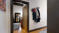 Located at 675 N Main in the heart of downtown Winston-Salem, NC, this one-bedroom, one-bathroom loft delivers a compelling blend of industrial character and modern comfort. The open-concept living and kitchen area anchors the space, featuring warm hardwood floors and soaring ceilings that amplify the sense of openness. Large, multi-pane factory-style windows flood the living room with natural light while offering views of the surrounding urban landscape — a signature nod to the building's industrial heritage.

The kitchen is well-appointed with dark wood cabinetry, granite countertops, stainless steel appliances, and pendant lighting, flowing seamlessly into the living area via a breakfast bar. Exposed ductwork overhead reinforces the loft's industrial aesthetic throughout.

The bedroom is a comfortable retreat with high ceilings, warm wood floors, and dual built-in closets framed in dark trim, providing generous storage. A wall-mounted coat rack near the entry adds everyday convenience.

The bathroom features a dark wood vanity with granite countertops, a wide mirror, and large-format tile flooring, offering a clean and functional design. Throughout the space, the consistent use of warm wood tones, dark trim accents, and thoughtful finishes creates a cohesive, urban-loft atmosphere ideal for city living.