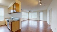 This single-story residence offers a well-organized layout that balances open communal spaces with private living quarters. The main living area is generously sized, featuring warm hardwood-style flooring, a ceiling fan, and large windows fitted with horizontal blinds that allow abundant natural light to fill the room. A glass-paneled door provides additional access, further brightening the space. Track lighting adds a functional design element overhead.

The kitchen is designed with efficiency in mind, featuring light wood cabinetry, granite-style countertops, and stainless steel appliances including a refrigerator, range, and microwave. A peninsula-style counter visually separates the kitchen from the adjacent dining and living areas while maintaining an open feel. A window above the sink provides natural light to the workspace.

Both bedrooms are carpeted and offer a calm, neutral atmosphere. Each room includes a closet for storage, and windows dressed with blinds allow for natural light while maintaining privacy.

The bathrooms continue the warm wood-tone aesthetic, featuring matching light wood cabinetry, white countertops, and hardwood-style flooring. One bathroom includes a sliding frosted-glass shower enclosure, while the other offers a spacious vanity with a wide mirror and strip lighting. The overall ambiance of the unit is clean, bright, and functional.