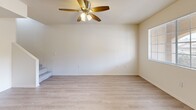 Located on W Broadway Blvd in Tucson, Arizona, this two-story residence offers a practical and well-designed layout spread across two floors. The main level houses an open-concept kitchen and living area finished with light wood-style flooring throughout. The kitchen is equipped with stainless steel appliances, including a refrigerator, range, microwave, and dishwasher, complemented by grey cabinetry and light countertops. A ceiling fan anchors the living room, which receives natural light through a window with blinds. A dedicated dining area features a chandelier pendant light and its own window with outdoor views of the surrounding Tucson landscape. A closet and a full bathroom with a tub-shower combo complete the main floor. Upstairs, a bright hallway with light wood-style flooring connects the two bedrooms, each carpeted and featuring large windows that invite natural light and views of the palm-tree-lined surroundings. The primary bedroom includes dual closets for ample storage. A second full bathroom serves the upper level. The home's clean, neutral palette and consistent finishes create a cohesive, move-in-ready atmosphere throughout.