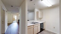 Located at 101 Legacy Ter in Chapel Hill, NC, this single-floor residence offers three bedrooms and three full bathrooms within a well-organized layout. The living area features light hardwood-style flooring and opens to a private balcony through a glass-paned door, bringing in natural light and outdoor views. The kitchen is equipped with light wood cabinetry, white countertops, a double-basin sink, a black dishwasher, and a full-size refrigerator — all flowing seamlessly into the dining area, which features matching hardwood-style flooring and ample space for a dining set. Each bedroom is carpeted and includes a ceiling fan, a window with natural views, and a closet — some fitted with built-in shelving and desk areas, providing functional study or workspace. The three full bathrooms each include a tub-shower combination with clean, white surrounds and chrome fixtures. A dedicated laundry room houses a full-size washer and dryer set with overhead wire shelving. Textured ceilings are consistent throughout the home, adding a classic residential character. The thoughtful floor plan and practical amenities make this a comfortable and functional Chapel Hill residence.