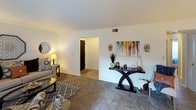 This single-story, two-bedroom, one-bathroom residence offers a thoughtfully arranged floor plan that maximizes functionality across its well-proportioned rooms. The living room features plush carpeting, neutral gray walls, and a sliding glass door that fills the space with natural light while providing direct access to a private outdoor patio. An adjacent dining area accommodates a full-sized table and is finished with wood-look flooring, a centered ceiling light fixture, and a window dressed with sheer curtains.

The kitchen is outfitted with rich, dark espresso cabinetry, granite-style countertops, a double stainless steel sink, and white appliances including a gas range and full-size refrigerator, offering ample storage and counter space throughout.

Both bedrooms are carpeted and feature windows that allow natural light to filter in. The primary bedroom is spacious enough to comfortably accommodate a full bed and additional furniture. The second bedroom offers flexibility as a guest room or home office.

The shared bathroom includes a dark vanity with a granite-style countertop, a single sink, and a tub/shower combination, maintaining the consistent, polished aesthetic found throughout the home.