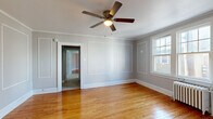 Located at 357 Morris St in Albany, NY, this single-floor, 3-bedroom, 1-bathroom unit offers a well-organized layout connecting bedrooms, a kitchen, bathroom, and hallway. Throughout the space, warm hardwood floors provide a consistent and inviting foundation, complemented by soft gray walls and crisp white trim. Crown molding and decorative wall paneling lend a classic architectural character to the rooms.

The spacious primary bedroom features elegant picture-frame wall molding, a ceiling fan with light fixture, and natural light from a double-hung window. The additional bedrooms also showcase hardwood floors, crown molding, ceiling fans, and natural light — one includes a traditional cast-iron radiator, highlighting the home's classic construction.

The kitchen is equipped with a gas range, refrigerator, and rich cherry wood cabinetry with crown molding detail above. Tile flooring and a practical layout make it a functional cooking space. Two interior doors lead to additional areas of the unit.

The bathroom features full white subway tile surrounding a tub-shower combo, classic black-and-white mosaic tile flooring, and a window providing natural ventilation and light. The overall ambiance of the unit is clean, bright, and defined by timeless architectural details consistent with Albany's historic residential character.