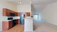 Located at 11234 W Peregrine Way in Greenfield, Wisconsin, this single-floor, 4-bedroom, 2-bathroom home offers a well-designed layout that balances functionality and comfort. The open-concept kitchen flows seamlessly into the living area, creating a spacious and connected feel. The kitchen is outfitted with rich warm-toned cabinetry, black appliances including a refrigerator, range, and microwave, light countertops, and hardwood flooring — all set beneath soaring vaulted ceilings that add an impressive sense of height and openness. The living area extends from the kitchen, featuring plush carpeting and a large window that invites natural light. The four bedrooms are carpeted and bright, with vaulted or angled ceilings in select rooms and windows that bring in additional daylight. Generous closet space, including a well-organized walk-in closet with wire shelving, provides ample storage. The two bathrooms feature tile flooring, white cabinetry, vanity mirrors, and clean, neutral finishes. A dedicated laundry room with a full-size washer and dryer adds everyday convenience. A staircase is also present within the home. Throughout, the neutral color palette and consistent finishes create a cohesive, move-in-ready ambiance.
