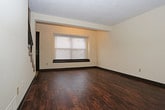 This two-story residence offers a well-organized layout with distinct living areas spread across both floors. The main level features rich, dark hardwood flooring throughout the living and entry areas, with a staircase connecting to the upper level. The entryway opens into a spacious living area filled with natural light from windows fitted with blinds. The kitchen is equipped with dark cabinetry, granite-style countertops, and a full suite of stainless steel appliances including a refrigerator, dishwasher, range, and over-the-range microwave, all set on classic tile flooring. A half bath or utility sink area is conveniently located adjacent to the kitchen. The upper level hosts multiple carpeted bedrooms, each featuring closets with built-in rods and windows that bring in natural light. The textured ceilings are consistent throughout the upper floor. Two full bathrooms serve the residence — one featuring a tub/shower combo with a dark vanity and granite-style countertop, and the other offering a glass-enclosed shower stall with matching cabinetry and tile flooring. Dark trim and door accents provide a cohesive design element throughout the entire space.