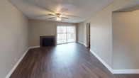 This single-story residence showcases a cohesive design throughout, unified by dark hardwood-style flooring and neutral warm-toned walls that create a consistent, contemporary aesthetic. The living area serves as the centerpiece of the unit, highlighted by a tile-surround fireplace, a ceiling fan with integrated lighting, and a sliding glass door fitted with vertical blinds that invites natural light and provides outdoor access. A dedicated bedroom space with its own ceiling fan offers a comfortable and well-proportioned layout.

The kitchen is designed for functionality and style, featuring dark espresso cabinetry, a white subway tile backsplash, granite-look countertops, and black appliances including a range and refrigerator. A peninsula counter connects the kitchen to the adjacent living space, making it well-suited for casual dining or entertaining. A window above the sink provides additional natural light.

The bathroom is neatly appointed with a dark vanity cabinet, a framed mirror, subway tile backsplash, and a full-size tub and shower combination. White baseboards and textured ceilings are consistent throughout the unit, contributing to a clean and well-maintained overall presentation.