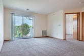 Located at 925 Harrington Dr in Madison, WI, this one-bedroom, one-bathroom unit offers a well-designed single-floor layout that makes efficient use of its space. The open-concept living and kitchen area serves as the heart of the unit, where warm hardwood-style flooring flows throughout the kitchen and transitions into plush carpeting in the living room. The kitchen is equipped with stainless steel appliances — including a refrigerator, electric range, and dishwasher — complemented by honey-toned oak cabinetry, light countertops, and a central island that adds additional prep and counter space. A ceiling fan overhead adds comfort to the living area, which is bathed in natural light from a sliding glass door that opens directly onto a private patio. From the patio, residents enjoy elevated views of the tree-lined neighborhood and open green spaces below. The bedroom is a comfortable, carpeted room featuring a large window with views of the surrounding greenery. Four closets throughout the unit provide generous storage. The full bathroom includes a wood-toned vanity with ample cabinet storage, a large mirror, and a full tub-shower combination, all finished with hardwood-style flooring. A hallway connects the main living spaces, completing this functional and neatly appointed unit.