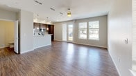 This two-story residence offers a thoughtfully designed layout that balances functionality and modern style. The main floor features an open-concept living and dining area with durable hardwood-style flooring that flows seamlessly throughout. Large windows and a glass-panel exterior door flood the space with natural light and provide outdoor views, while a ceiling fan adds comfort to the generously sized living room. A staircase leads to the upper level, and a built-in desk nook provides a convenient workspace near the entry.

The kitchen is a standout feature, equipped with rich dark-toned cabinetry, stainless steel appliances including a range, microwave, and refrigerator, and crisp white countertops. A peninsula with pendant lighting above offers additional prep space and a casual dining option.

The bedrooms are carpeted for warmth and comfort, each featuring natural light from well-placed windows and ample closet storage with sliding or panel-style doors. The bathrooms are finished with wood-look flooring, dark vanity cabinetry, light stone-style countertops, and clean white fixtures. One bathroom includes a walk-in glass-enclosed shower, adding a refined touch. Overall, the space presents a clean, contemporary aesthetic with practical finishes throughout.
