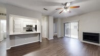 This single-story residence in Austin, Texas offers a thoughtfully arranged layout across two bedrooms and three bathrooms. The open-concept living and dining area serves as the heart of the home, featuring durable wood-style flooring, a ceiling fan with integrated lighting, and a white-surround fireplace flanked by a sliding glass door fitted with vertical blinds. The door provides direct access to an outdoor space while drawing in natural light.

The kitchen connects seamlessly to the main living area via a breakfast bar-style pass-through. It is outfitted with white cabinetry, a tile backsplash, and stainless steel appliances including a range, microwave, and refrigerator. Wood-style flooring continues throughout the main living spaces.

The bedrooms are carpeted for added comfort and include sliding closets with wire shelving. Natural light enters through windows dressed with vertical blinds. The bathrooms are clean and functional, featuring white cabinetry, wide vanity countertops with vessel sinks, and tiled tub-shower combinations. A textured ceiling is consistent throughout the residence, contributing to its cohesive, understated aesthetic.
