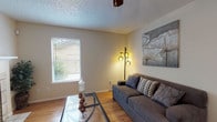 This single-story, 2-bedroom, 2-bathroom residence offers a thoughtfully organized layout with consistent wood-look flooring running throughout the main living areas. The living room serves as a central gathering space, featuring a tile-surround fireplace, a natural light-admitting window with blinds, and a textured ceiling. The dining area is positioned adjacent to the living space and benefits from a corner window arrangement that draws in additional natural light, enhancing the room's open feel.

The kitchen is functionally designed with white cabinetry, open shelving, granite-style countertops, and black appliances including a range, refrigerator, and dishwasher. A double sink sits beneath a window, adding brightness to the workspace.

Both bedrooms are carpeted and include windows that provide natural light and outdoor views. Ceiling fans are present for added comfort. Closet storage is available in the bedrooms, offering practical organization options.

The two bathrooms include tub-shower combinations with tiled surrounds, white cabinetry, and granite-style countertops. Wood-look flooring carries through the bathroom spaces, maintaining a cohesive aesthetic throughout the home.