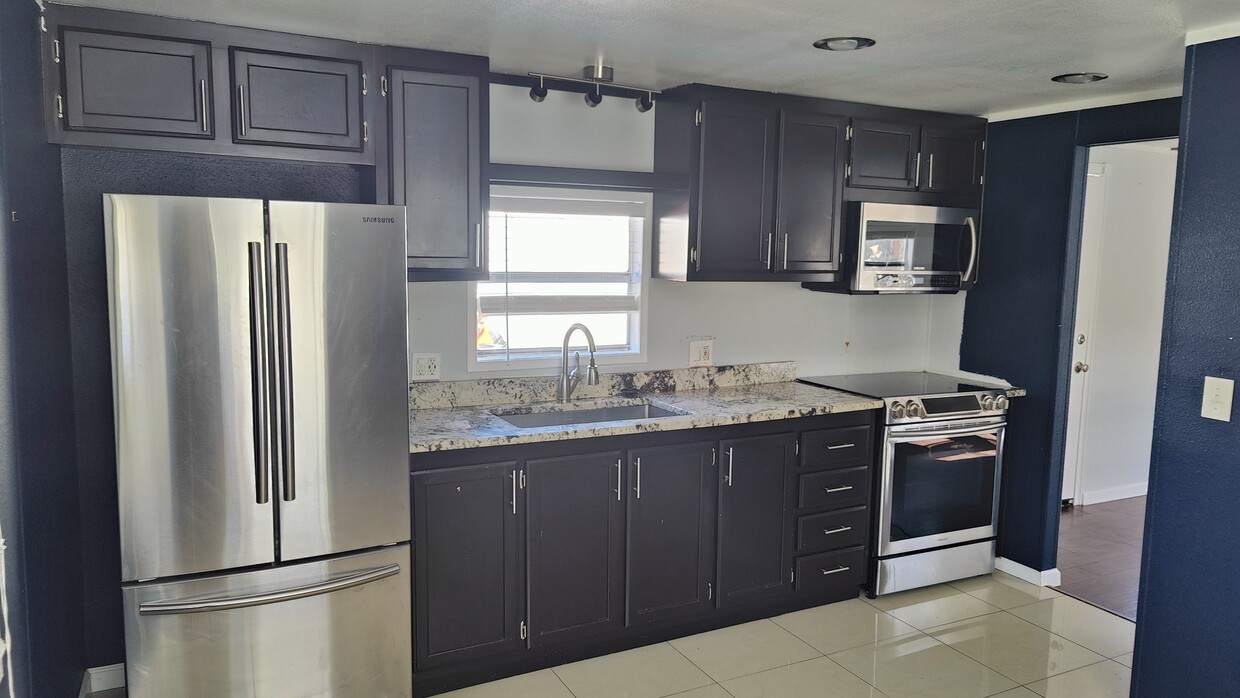 Cocina con refrigerador de acero inoxidable, estufa eléctrica y microondas. - 7905 Harwell St