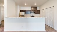 Located in Post Falls, Idaho, this well-appointed 2-bedroom, 2-bathroom residence offers a thoughtfully designed single-level layout. The open-concept kitchen is a standout feature, showcasing dark cabinetry, marble-look countertops, stainless steel appliances including a refrigerator, electric range, and over-the-range microwave, and wood-look plank flooring that extends throughout the main living areas. A raised breakfast bar separates the kitchen from the spacious living area, which benefits from large windows and a door providing access to the outdoors, filling the room with natural light.

Both bedrooms are carpeted for comfort and feature generous windows dressed with vertical blinds, allowing ample daylight and views of the surrounding area. The primary bedroom is notably spacious and is served by a private en-suite bathroom with a marble-look vanity countertop, dark cabinetry, wood-look flooring, and a shower-tub combination. A dedicated closet with wire shelving offers practical storage. The second bathroom mirrors the same clean, modern finishes. A walk-in closet with full wire rack shelving system rounds out the storage options. The unit's neutral palette and modern finishes create a bright, clean, and functional living environment.