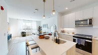 Located at 3 Executive Drive in Evesham, NJ, this well-appointed one-bedroom, two-bathroom residence offers a thoughtfully designed open-concept layout with clean, modern aesthetics. Light wood-style flooring flows throughout the space, complementing a bright, neutral color palette.

The kitchen is a standout feature, showcasing a two-tone design with crisp white upper cabinetry and warm natural wood lower cabinets, a white subway tile backsplash, stainless steel appliances, and a central island with seating — perfect for casual dining or entertaining. Globe pendant lights with brass hardware add a stylish finishing touch overhead.

The living room is bathed in natural light from large windows dressed with sheer curtains, creating a warm and airy atmosphere. A private entry door provides added convenience.

The bedroom is a serene retreat, comfortably sized with large windows offering outdoor views, light wood flooring, and ample space for furnishings. It connects directly to a sleek en-suite bathroom featuring large-format tile flooring and a glass-enclosed shower.

A second full bathroom provides additional convenience for guests. A dedicated closet completes the layout, maximizing storage. The overall design balances contemporary style with functional living.